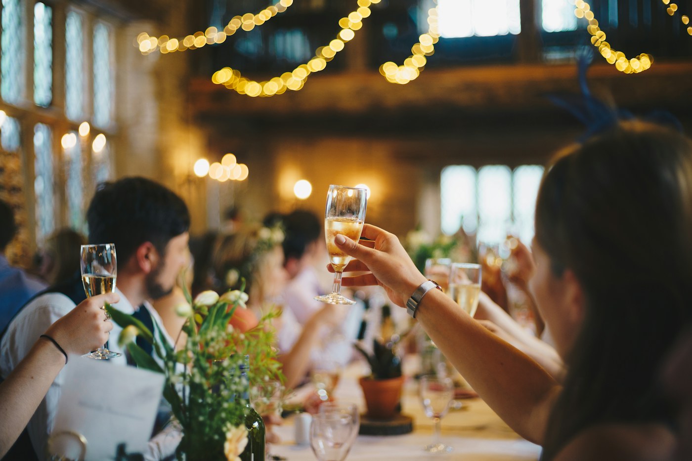 Guests raising a toast under string lights at an evening event