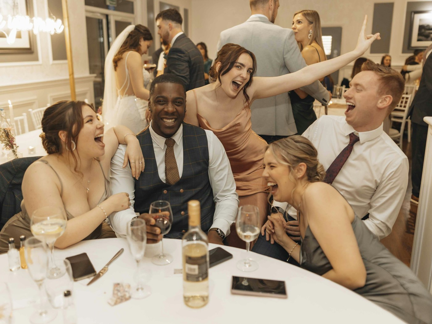 Wedding guests laughing together at a reception table