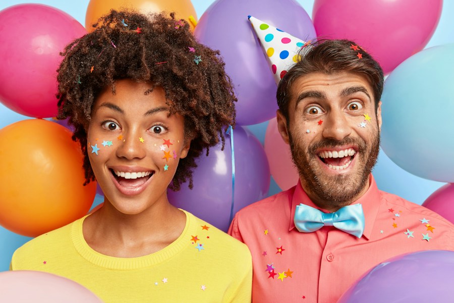 Two guests with balloons and party hats